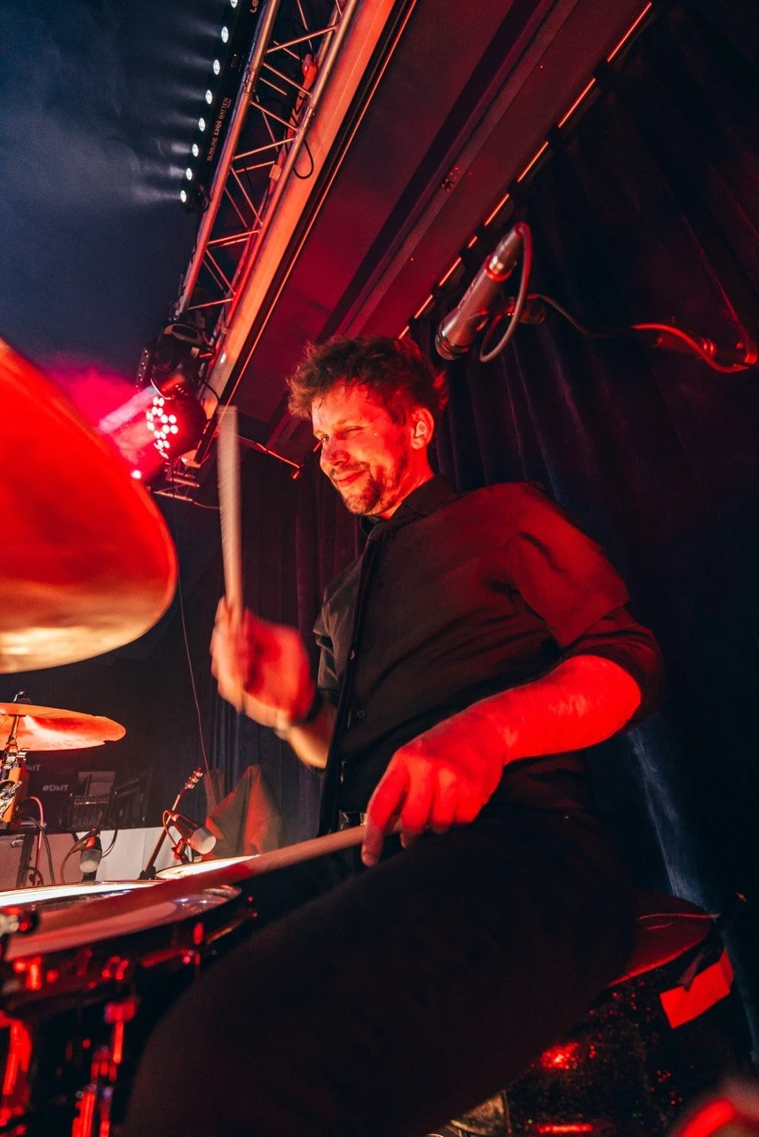 Callum drumming in action with red stage wash