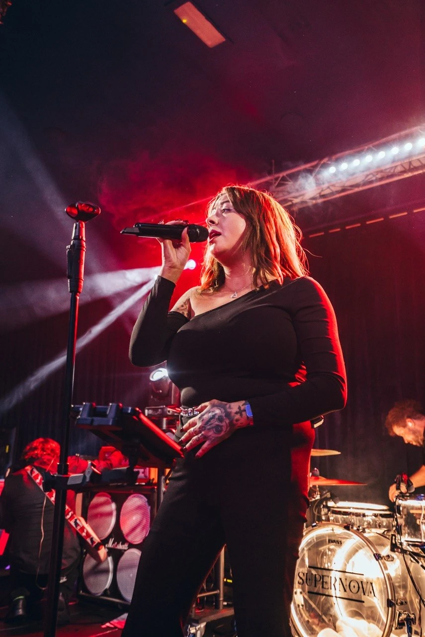 Female vocalist close-up performing with red backlight and haze