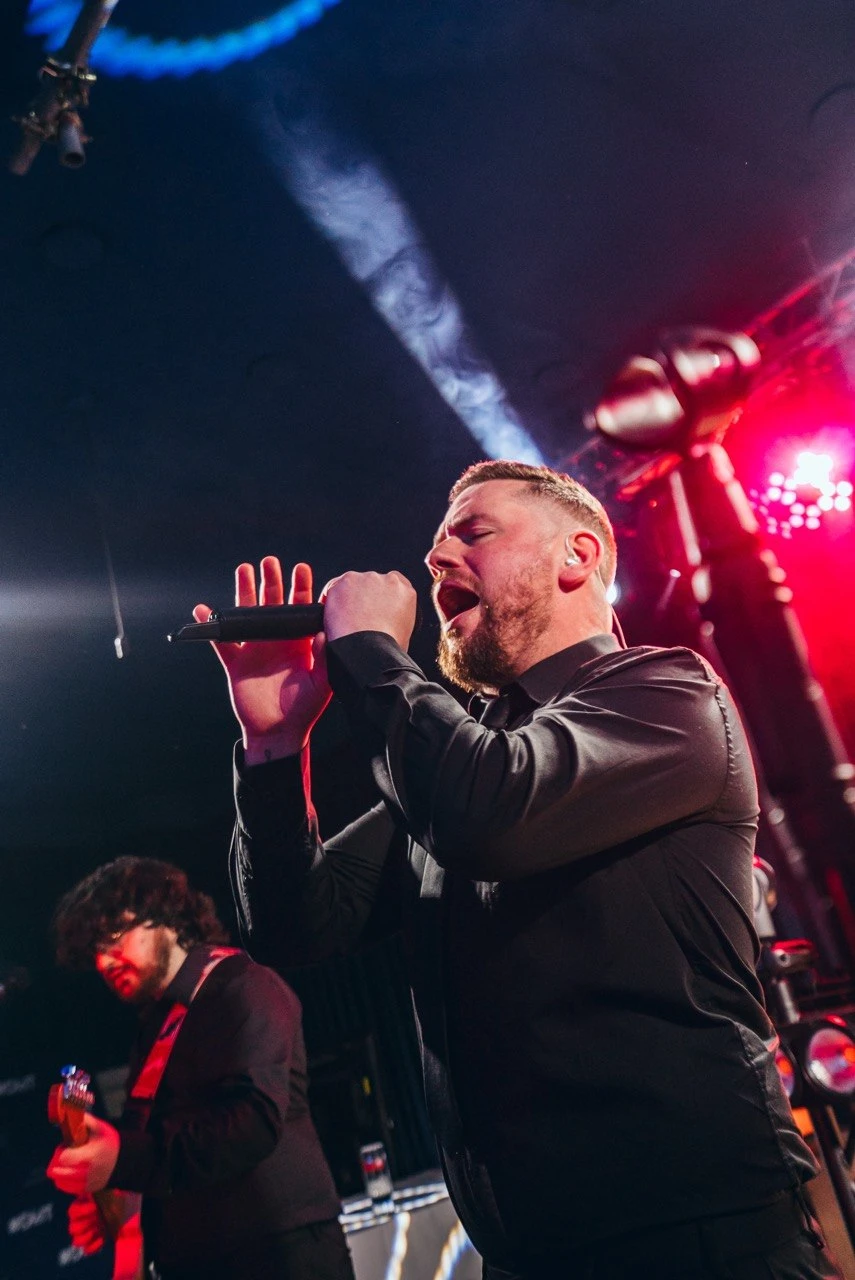 Male vocalist performing with red and blue stage lighting